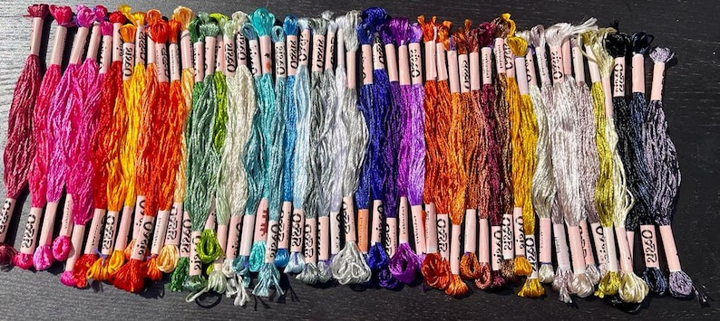 Puede incluir: Una colecci&oacute;n de 40 carretes de hilo de bordar en varios colores, incluyendo rosa, naranja, amarillo, verde, azul, morado, rojo, marr&oacute;n y plateado. Cada carrete est&aacute; etiquetado con "DMC" y tiene un n&uacute;mero impreso.
