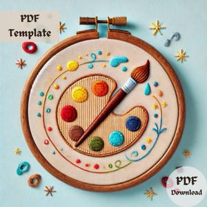 May include: Embroidered artwork featuring a wooden paint palette with colourful paint dots and a paintbrush. The design is surrounded by a decorative floral pattern and stars. The artwork is displayed in a wooden embroidery hoop.