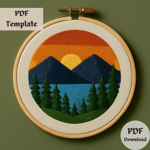 May include: Embroidered hoop art featuring a sunset over a lake with mountains and trees. The sunset is a gradient of orange, yellow, and red. The mountains are dark blue, and the trees are green. The lake is a light blue.