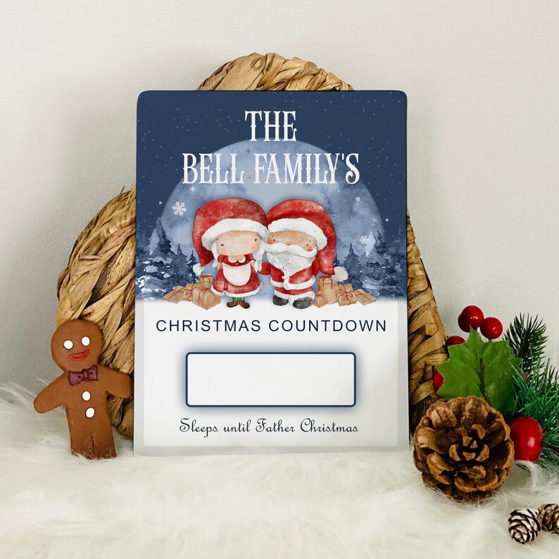 K&ouml;nnte beinhalten: Ein blaues und wei&szlig;es Weihnachts-Countdown-Schild mit einem personalisierten Familiennamen "The Bell Family's". Das Schild zeigt eine Cartoon-Illustration von Weihnachtsmann und Frau Claus mit Geschenken. Der Text "Christmas Countdown" und "Sleeps until Father Christmas" ist auf dem Schild gedruckt.