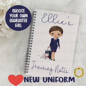 May include: A white spiral notebook with a cartoon illustration of a woman in a blue flight attendant uniform holding a suitcase. The notebook has the text "Ellie's Training Notes NEW UNIFORM" printed on the front.