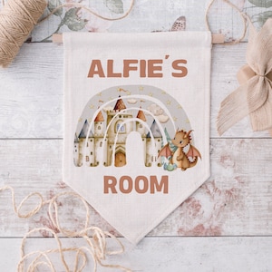May include: A beige canvas banner with the text "Alfie's Room" in brown lettering. A rainbow with a castle and a dragon is in the centre of the banner.
