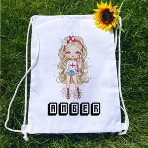 May include: White drawstring bag featuring a cartoon illustration of a blonde girl with blue eyes, wearing a white shirt with a cross, denim shorts, and gladiator sandals. The name "AMBER" is printed in black block letters at the bottom.