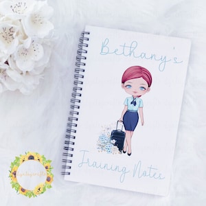May include: A white spiral bound notebook with a blue and white illustration of a woman with a suitcase. The notebook has the text "Bethany's Training Notes" on the front.