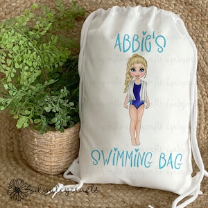 May include: White drawstring bag with a blue and white illustration of a girl in a swimsuit. The bag has the text "ABBIC'S SWIMMING BAG" printed on it.