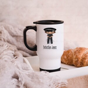 May include: White travel mug with a black handle and lid. The mug features a cartoon illustration of a police officer with the text "Detective Jones".