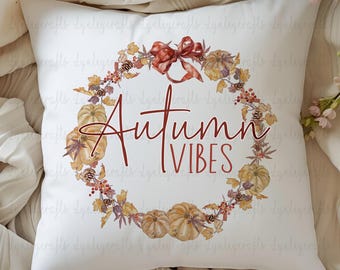 May include: White square pillow with a watercolor wreath design featuring pumpkins, leaves, and berries. The wreath surrounds the words "Autumn Vibes" in a dark red script. A dark red bow is at the top of the wreath.