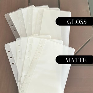 May include: Two stacks of clear plastic sheet protectors, one labelled "GLOSS" and the other "MATTE". The sheets have holes for a binder.