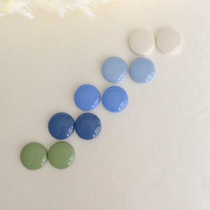 Op de afbeelding: Een set van drie keramische mokken met een gespikkelde, matte afwerking. De mokken zijn in tinten crème, lichtgrijs en donkergrijs. Elke mok heeft een eenvoudig, minimalistisch ontwerp, perfect voor koffie of thee.