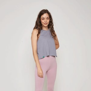 May include: A woman is wearing a light gray sleeveless crop top and pink leggings.