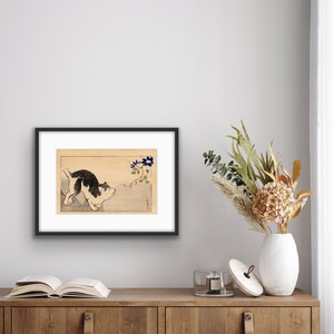 Peut inclure: Un chien noir et blanc regardant une fleur bleue sur une vigne. L'image est dans un cadre noir et se trouve sur une &eacute;tag&egrave;re en bois avec un livre et un vase de fleurs.