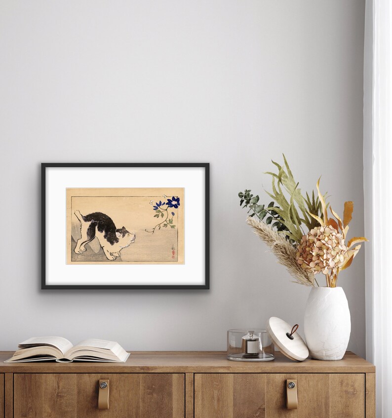 Peut inclure: Un chien noir et blanc regardant une fleur bleue sur une vigne. L'image est dans un cadre noir et se trouve sur une &eacute;tag&egrave;re en bois avec un livre et un vase de fleurs.