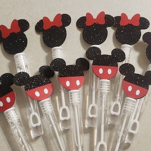 May include: A set of ten clear plastic bubble wands with red and black Mickey Mouse character toppers. The toppers are made of glitter paper and feature Mickey Mouse's ears, face, and signature red shorts with white polka dots.