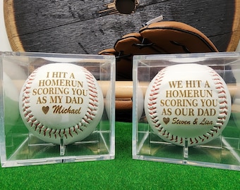 May include: Two baseballs in clear display cases with personalized messages. The first baseball reads "I hit a homerun scoring you as my dad Michael". The second baseball reads "We hit a homerun scoring you as our dad Steven & Lisa".