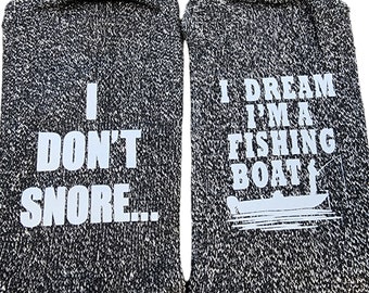 May include: A pair of gray socks with white text. One sock says "I don't snore..." and the other sock says "I dream I'm a fishing boat".