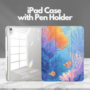 May include: A clear iPad case with a pen holder and a folding cover featuring a vibrant underwater scene with orange clownfish, blue coral, and orange sea anemones. The text "iPad Case with Pen Holder" is printed in white above the device.