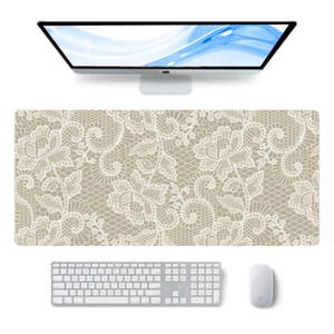 May include: A rectangular desk mat featuring a beige background with a white floral lace pattern. The mat is positioned on a surface below a computer monitor, a white keyboard, and a white computer mouse, creating a coordinated workspace setup.