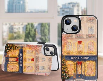 Puede incluir: Dos fundas de teléfono con una ilustración detallada de una fachada de librería. El diseño presenta un toldo azul con las palabras "BOOK SHOP", luces festivas y un árbol de Navidad. Las fundas tienen un borde negro y un interior blanco.