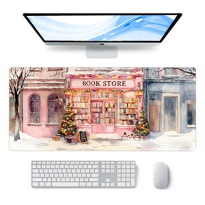 May include: A rectangular mouse mat with a watercolour illustration of a pink book store with the text "BOOK STORE". The scene includes Christmas trees, snow, and a keyboard, mouse, and monitor.