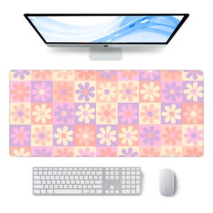 May include: A large rectangular desk mat with a colourful floral pattern in a checkerboard design. The flowers are in shades of pink, purple, and yellow. A computer keyboard, mouse, and monitor are also visible.