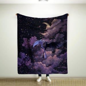 Puede incluir: Una manta con una escena de fantasía con dos dragones en vuelo contra un cielo estrellado. Un dragón es blanco y el otro negro, sobre un fondo de nubes púrpuras y una luna creciente.