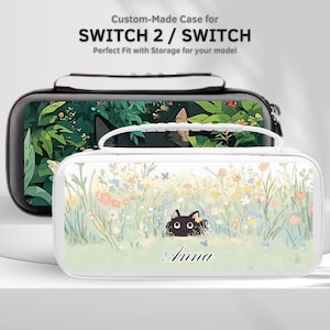 May include: Two custom-made Switch 2 / Switch cases. One is black with a green foliage design. The other is white with a cat peeking out of a field of flowers. The name "Anna" is printed on the white case.