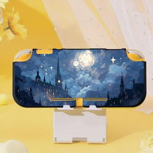 May include: A yellow and navy blue Nintendo Switch Lite case featuring a nighttime cityscape design. The case has a vibrant illustration of a moonlit sky, stars, and buildings. The case is resting on a white stand.