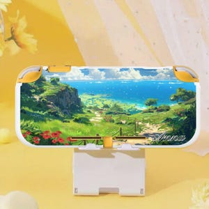 以下が含まれることがあります： 海への道を描いた風景デザインの白と黄色のNintendo Switch Liteケース。ケースには「Anna」という名前がプリントされています。ケースは白いスタンドで支えられています。