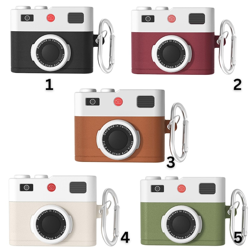 May include: Five different colored camera-shaped phone cases with a silver carabiner. The cases are black, red, brown, white, and green. Each case has a white front with a black lens and the text "Designed in California" printed on the front.