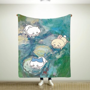 May include: A green, blue and yellow abstract patterned throw blanket with three cartoon animals: a white cat with a blue bow, a white bear and a yellow bunny rabbit.