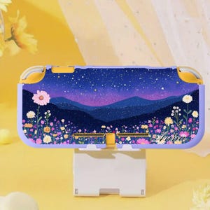 Puede incluir: Una funda morada y amarilla para Nintendo Switch Lite con un diseño de cielo estrellado, montañas y un campo de flores coloridas. La funda tiene el nombre "Anna" impreso.