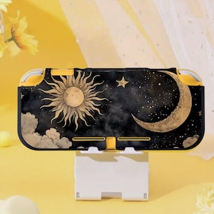 May include: A black and gold Nintendo Switch Lite case with a celestial design. The case features a sun, moon, stars, and clouds. The case is yellow and black.