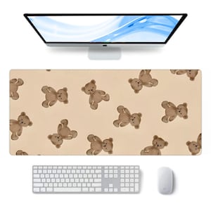 Puede incluir: Alfombrilla de escritorio rectangular beige con un patrón repetido de osos de peluche marrones. También se ven un monitor de ordenador, un teclado y un ratón. Los osos de peluche están en varias poses.