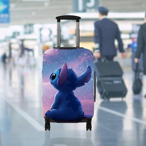 May include: A blue suitcase featuring a cartoon Stitch character set against a starry sky. The luggage has a retractable handle and four black wheels. The background is blurred, implying an airport or travel environment.