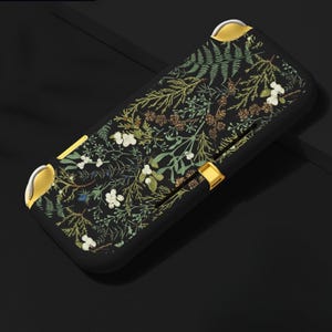 May include: Black Nintendo Switch case with a floral pattern featuring white flowers, green leaves, and gold accents.