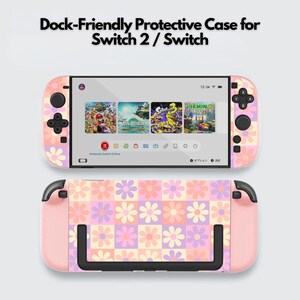 Puede incluir: Una funda protectora rosa con estampado floral para una Switch 2 / Switch. La funda presenta un patrón de margaritas en rosa, morado y blanco. La pantalla muestra iconos de juegos. El texto "Dock-Friendly Protective Case for Switch 2 / Switch" está en la parte superior.
