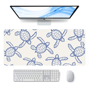 May include: A rectangular desk mat featuring a repeating pattern of blue sea turtles on an off-white background. A white keyboard, mouse, and computer monitor are also visible.