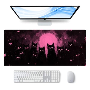 May include: A rectangular desk mat featuring a dark, atmospheric scene with multiple black cats silhouetted against a large, vibrant pink moon. The design includes scattered small pink butterflies and splatters, creating a high-contrast graphic illustration on a deep black background.