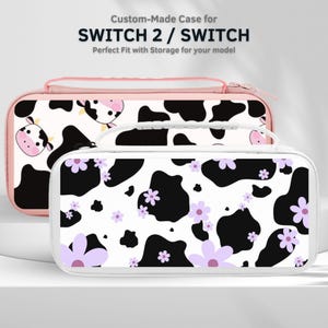 May include: Two custom-made cases for SWITCH 2 / SWITCH. The top case is pink with a cow print design. The bottom case is white with a black cow print and purple flower accents. Both cases have a zipper closure and a handle.