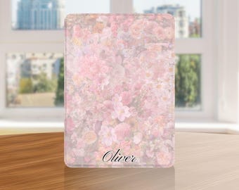 May include: A rectangular item with a floral pattern in shades of pink and white. The design features various flowers, with the name "Oliver" in a cursive font at the bottom. The item is placed on a wooden table.