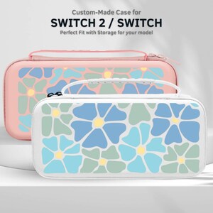May include: Two floral-patterned cases for a Switch 2 / Switch. The front case is white with blue, green, and yellow flower designs. The back case is pink with a similar floral pattern. The cases have zippers and a handle.
