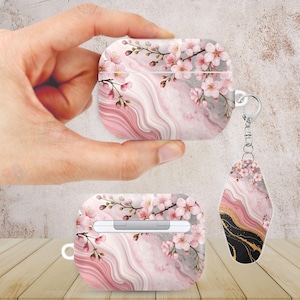 Puede incluir: Funda para AirPod con diseño de mármol rosa y gris y diseño floral. La funda presenta un patrón de mármol rosa y gris con flores de cerezo rosas. Se adjunta un llavero a juego.