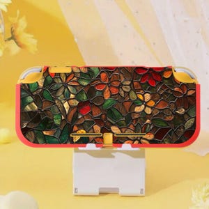 Puede incluir: Una funda roja y amarilla para Nintendo Switch Lite con un diseño floral de vidriera. La funda presenta un mosaico colorido de formas de flores y hojas verdes, marrones, naranjas y rojas. La funda está sobre un soporte blanco.