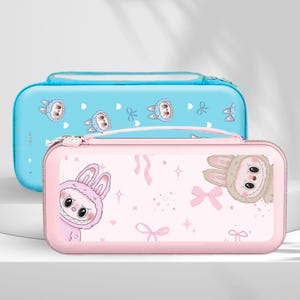 May include: Two zippered cases, one light blue and one pink, featuring cartoon bunny designs. The blue case has a handle and a bunny pattern with hearts. The pink case has a bunny design with bows and stars.