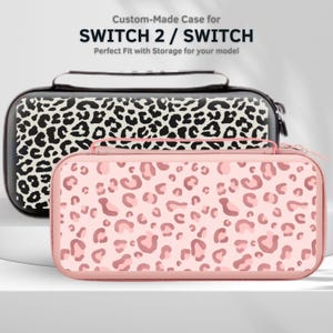 May include: Two custom-made cases for SWITCH 2 / SWITCH. One case is black with a white leopard print, and the other is pink with a darker pink leopard print. The cases have a zipper closure and a handle.