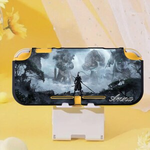 May include: A yellow and black video game console case featuring a fantasy scene with a warrior and monsters. The case has the name "Anna" printed on it. The case is resting on a white stand.