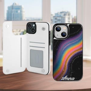 May include: A white wallet-style phone case with interior card slots and a magnetic closure, paired with a black phone case featuring a colorful, swirling rainbow nebula design and the name Anna printed in white script at the bottom.