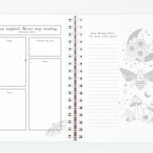 Pu&ograve; includere: Un taccuino a spirale bianco con un'illustrazione in bianco e nero di una farfalla sulla pagina sinistra. La pagina destra presenta un'illustrazione in bianco e nero di una luna, stelle, un'ape e funghi. Il testo "Stay inspired. Never stop creating." &egrave; in alto sulla pagina sinistra. Il testo "Idea Dump Zone (to deal with later)" &egrave; in alto sulla pagina destra.