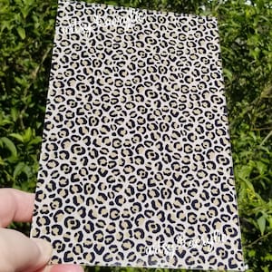 May include: A sheet of clear acrylic with a leopard print design. The print is in black, tan, and white.