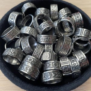 Peut inclure: Une collection d'anneaux en argent avec des motifs floraux complexes, présentés dans un bol en velours noir.